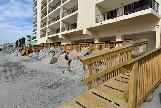 Wood stairway with railings descending from the Atalaya Towers deck toward the beach
