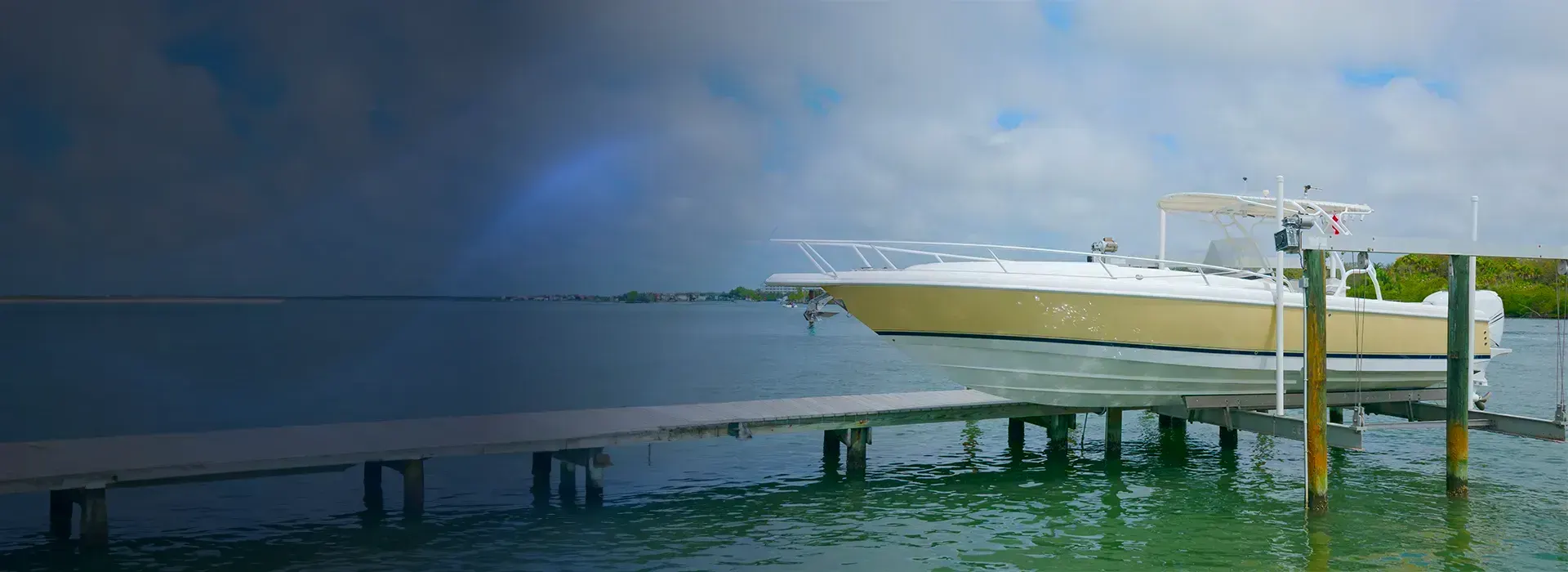 Boat secured on a waterfront lift beside a fixed dock