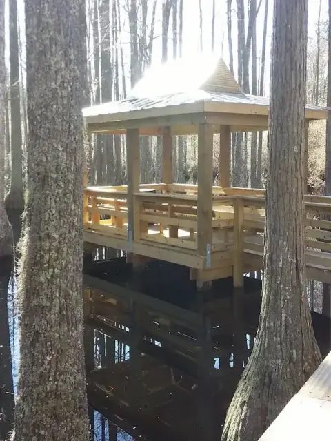 Covered timber pier standing over water among cypress trees at The Park in Murrells Inlet