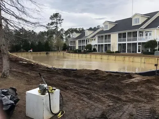 Retention pond at The Villas with a timber perimeter beside residential buildings in Murrells Inlet